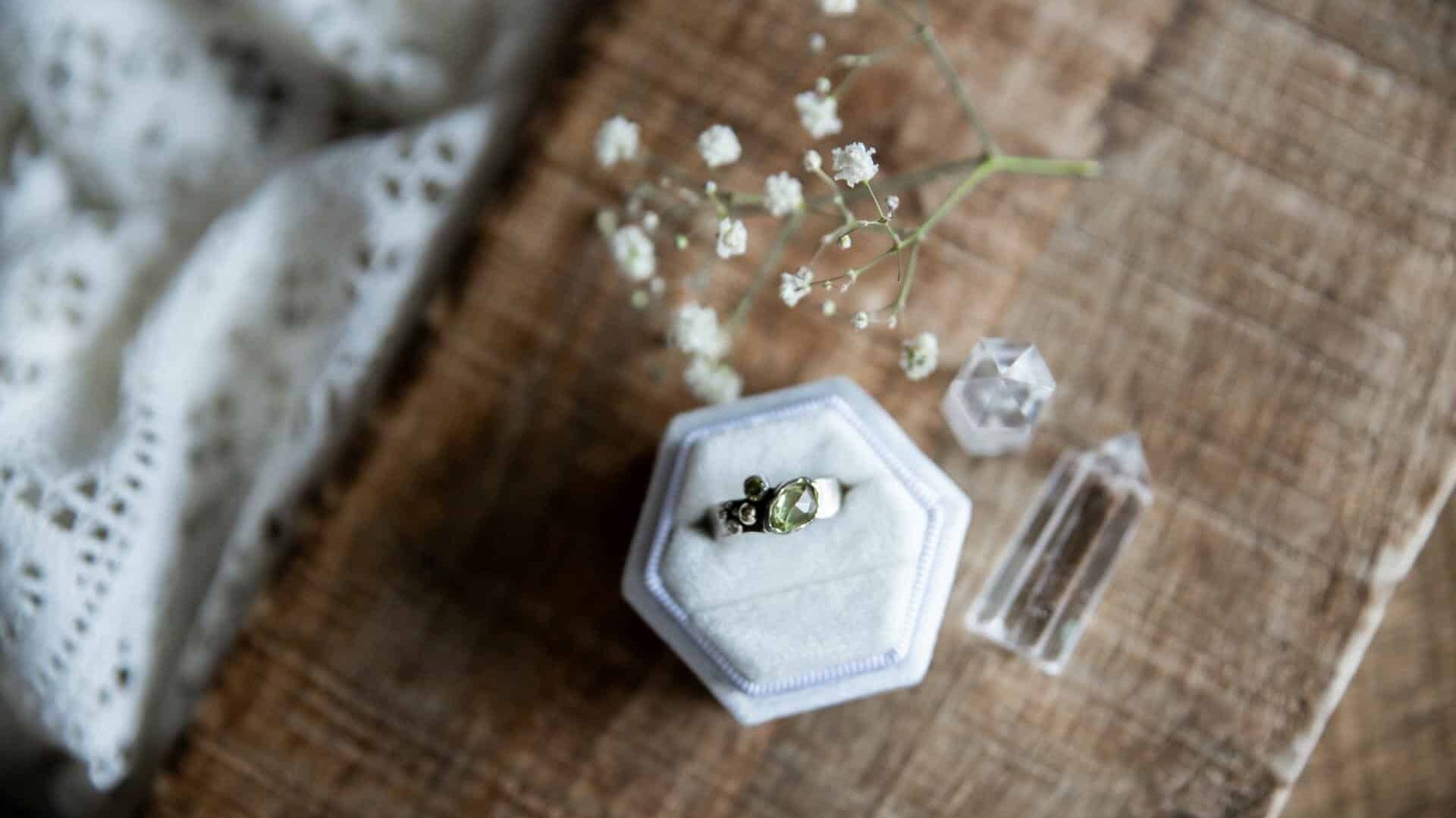 A stunning piece of vintage and estate jewelry in a ring box surrounded by flowers.