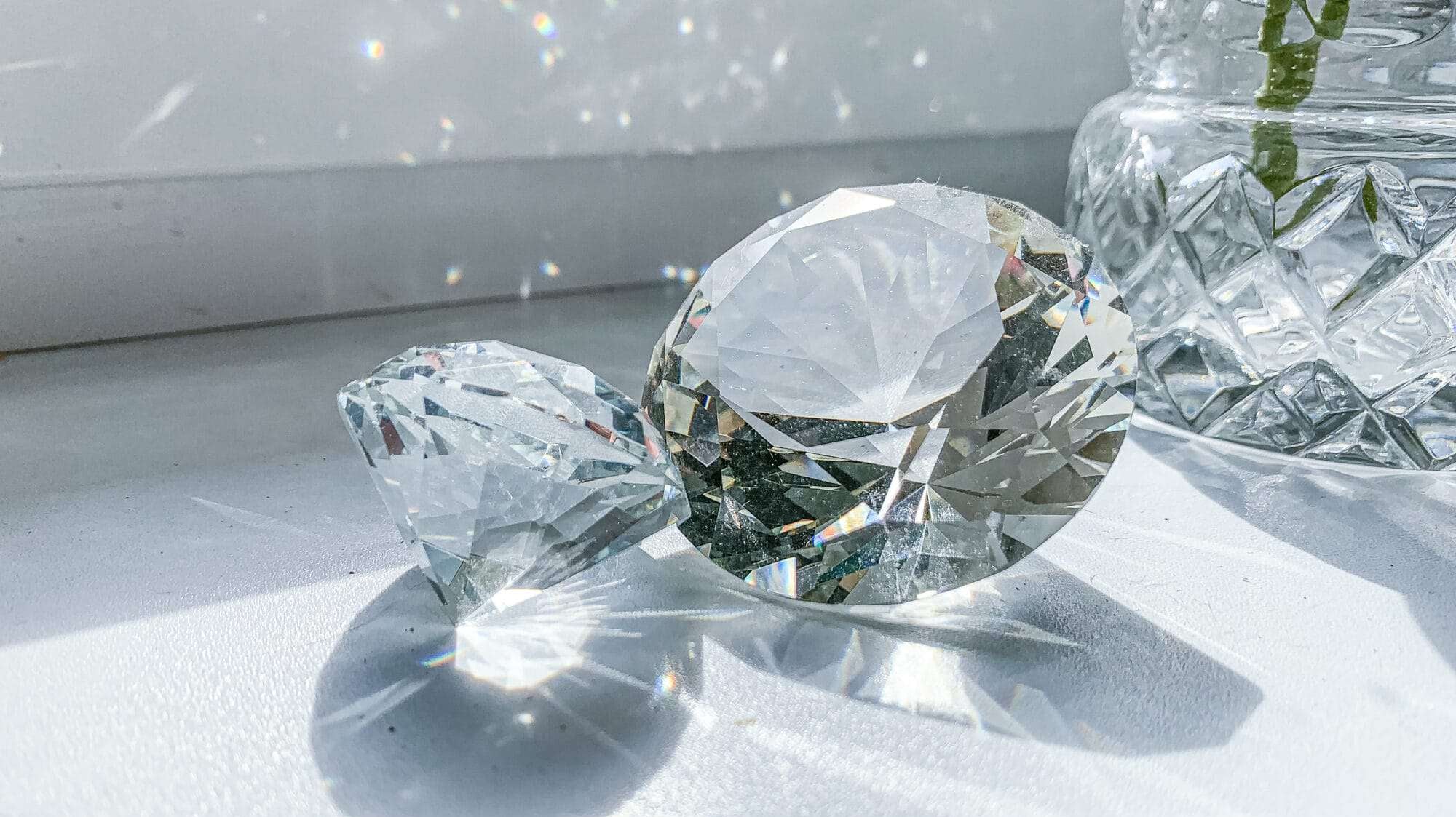 2 large diamonds on a. white table sparkling in the sunlight
