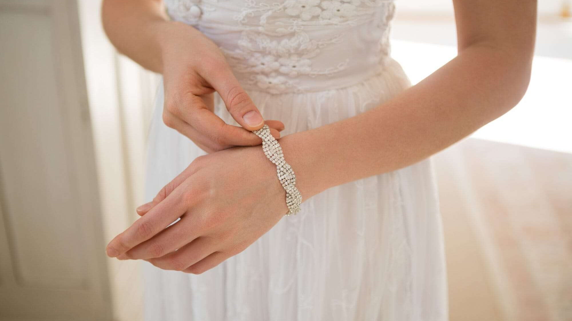 Midsection of bride wearing bracelet while standing at home