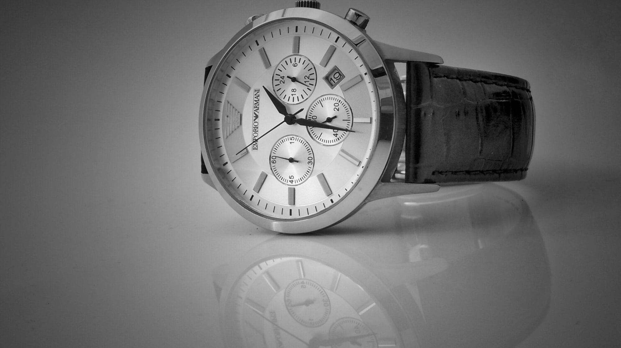 Luxury switch watch with leather band, in black and white on a glossy surface