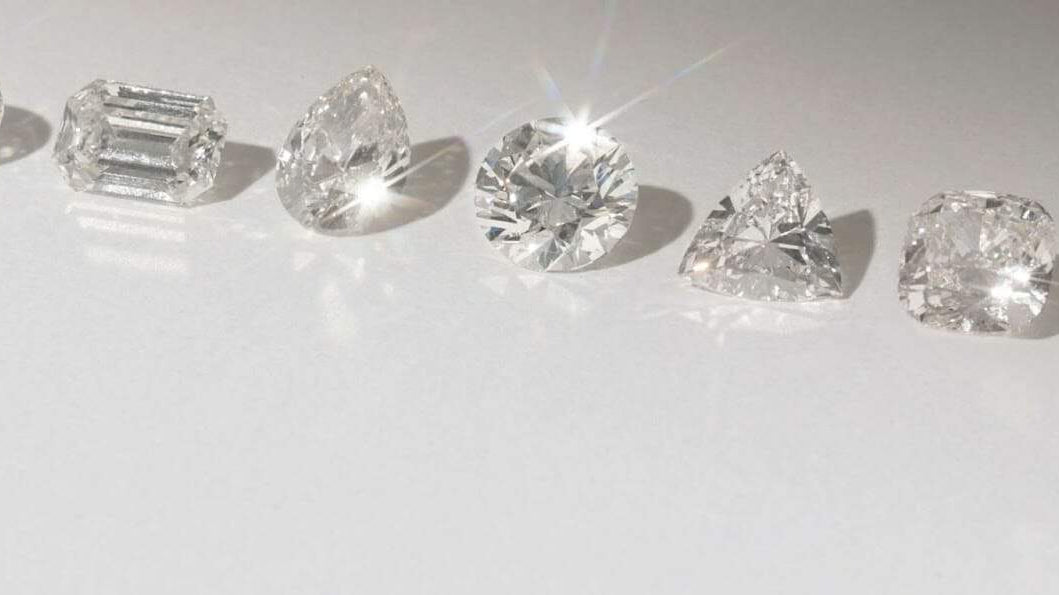 Multiple diamond shapes including - pear, emerald, round, heart cut diamonds, sitting on a white background