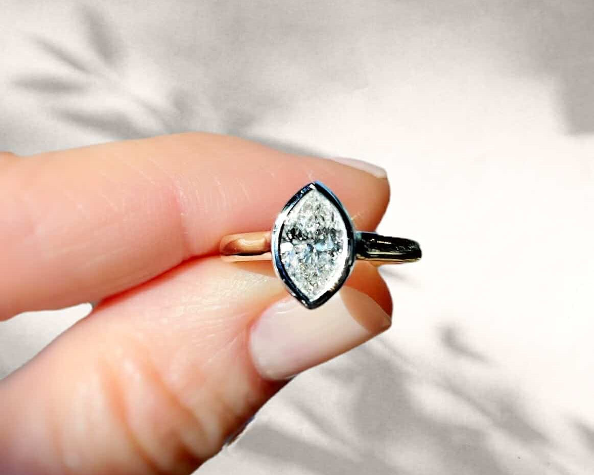 A stunning bezel setting with a beautiful ADX diamond being held.