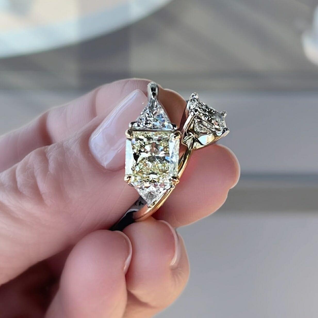 Someone holding two-tone metal rings in her finger tips.