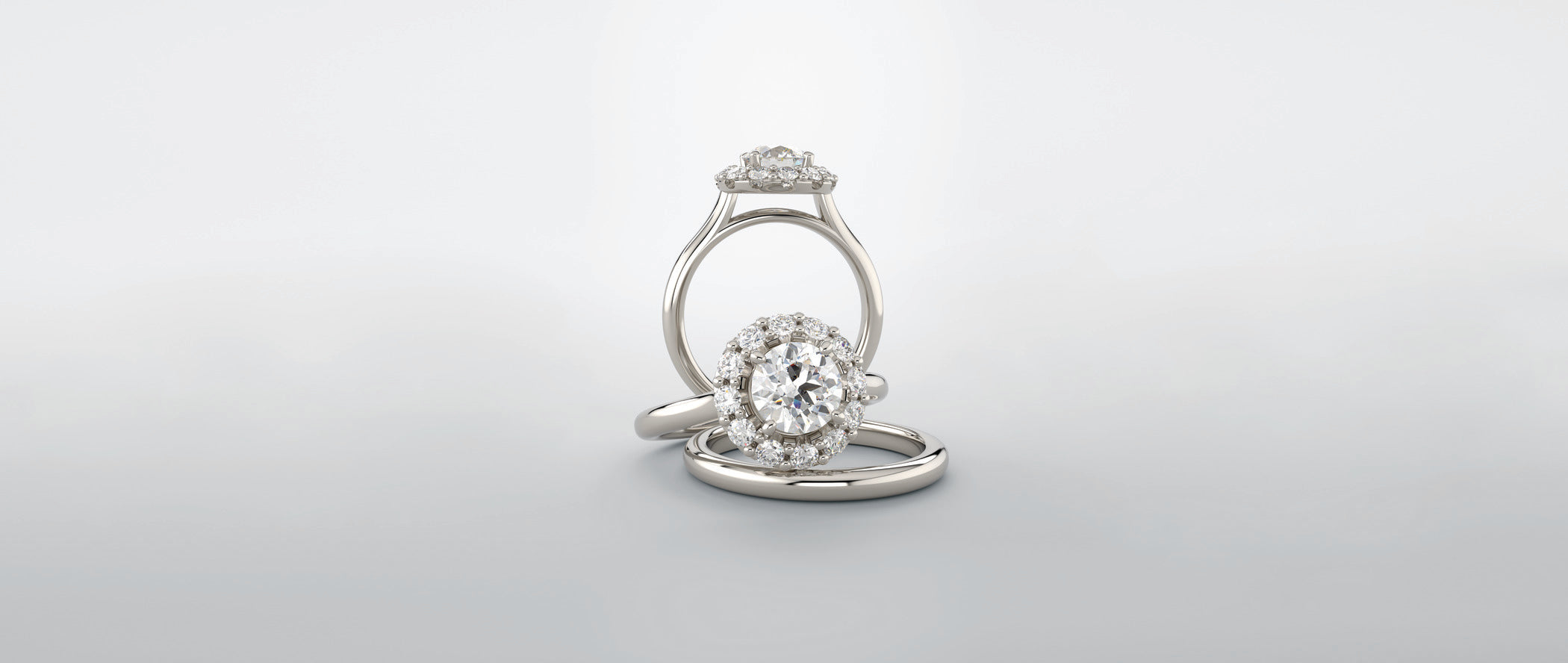 Oval diamond engagement ring featuring a cathedral setting and a round diamond halo, paired with a matching diamond band, displayed in a clean light gray studio setting.