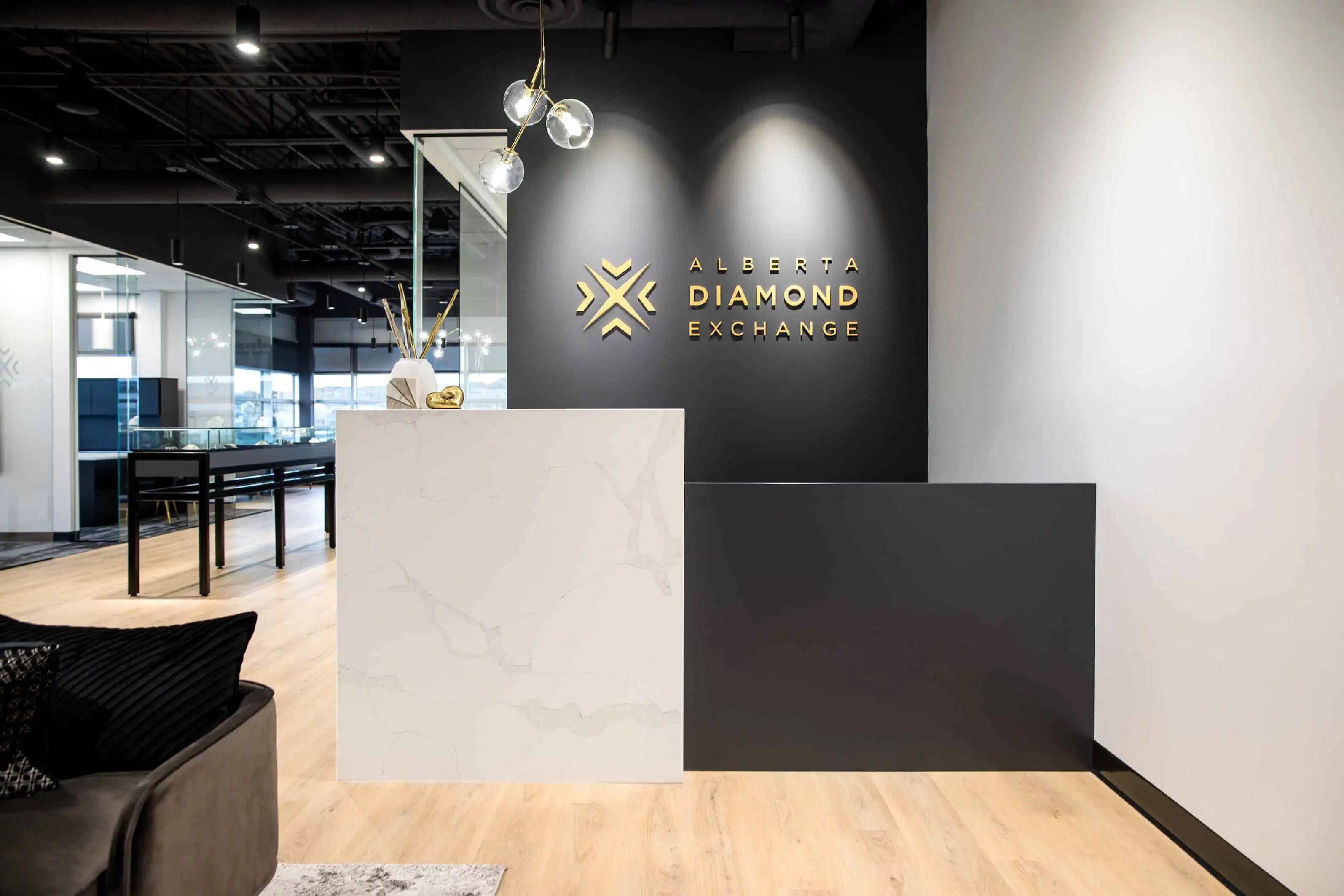 Reception area of Alberta Diamond Exchange featuring a modern marble desk and illuminated brand logo inside a contemporary jewelry showroom.